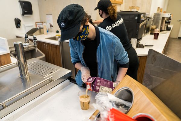 person in mask pours coffee over ice