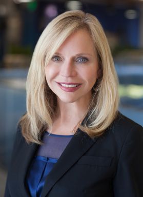 photo of blond woman with shoulder-length hair in dark suit jacket