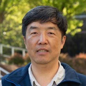 Headshot of WVU researcher Xingbo Liu. He is pictured standing outside with greenery behind him. He is wearing a navy blue fleece jacket over a button up shirt. He has short, black hair. 