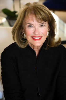 Headshot of WVU honoree Pam Maphis Larrick. She is pictured inside wearing a black top. Her shoulder length hair is dark blonde and she is wearing red lipstick.