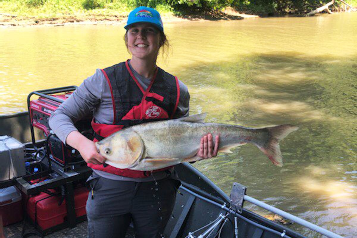woman in boat holds large fish