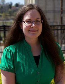 Brunette woman with glasses and a green shirt.