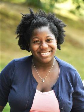 portrait of smiling black woman in pink shirt and blue cardigan