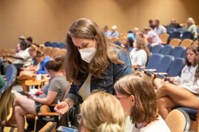 Studying is done in an auditorium is helping students while wearing a mask to help prevent the spread of COVID-19.