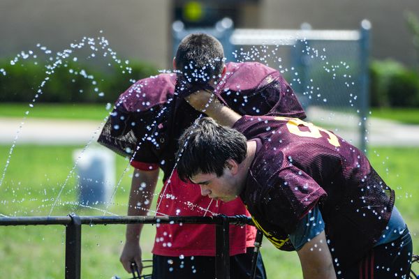 young men stand in water spray