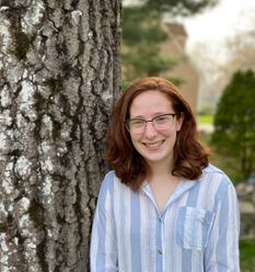 young woman, glasses, standing by tree