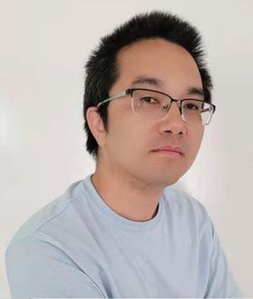 Headshot of WVU professor Michael Hu. He is pictured against a light colored background wearing a light blue shirt. His black hair is cut short and he wears glasses. 