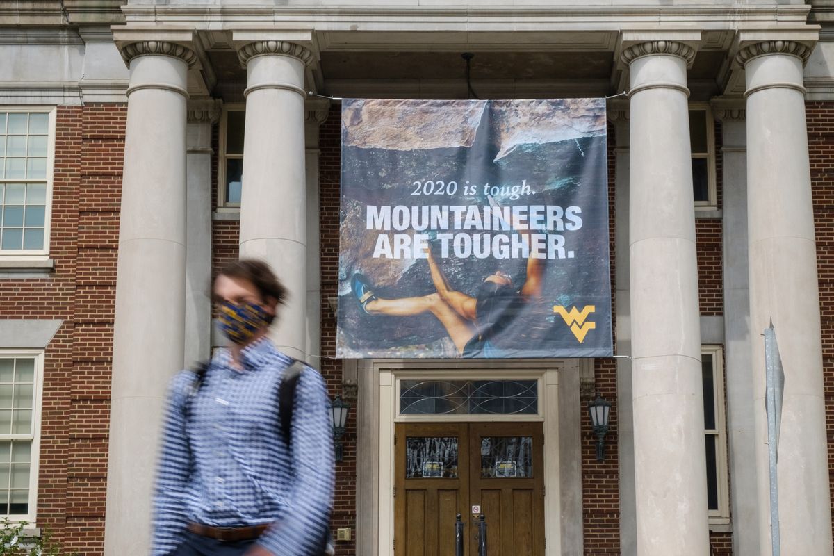 person walks out of building with banner that says Mountaineers are tougher