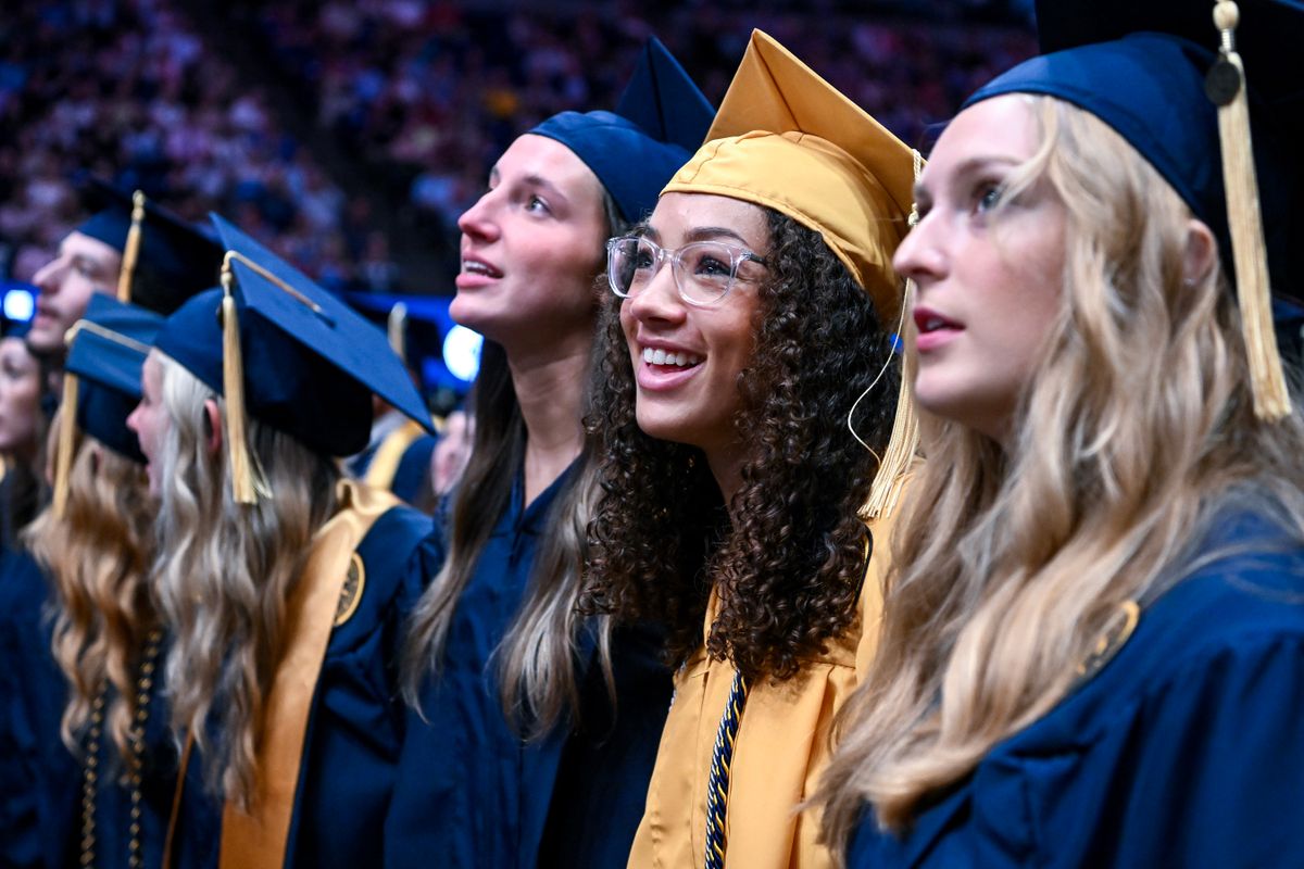 Three graduatees stand smiling at the conclusion of the College of Applied Human Sciences commencement ceremony. One in the middle is wearing a gold and blue cap and gown and clear-rimmed glasses. The two others are wearing blue caps and gowns.