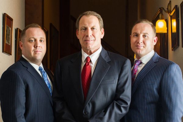 Three men pose in suits