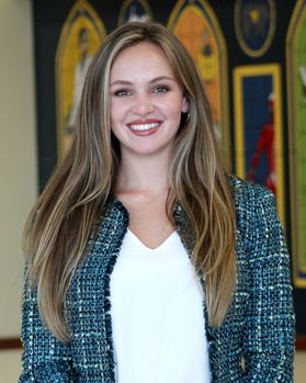 Headshot of WVU nursing student Shelbey Groves. She is pictured inside wearing a blue tweed coat over a white blouse. She has long blonde hair. 
