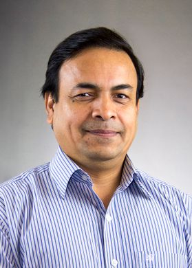 Headshot of WVU researcher Mahfuz Rahman. He is pictured in front of a light gray background wearing a blue striped dress shirt. He has short, black hair. 