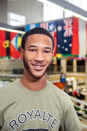 A smiling man with flags in the background