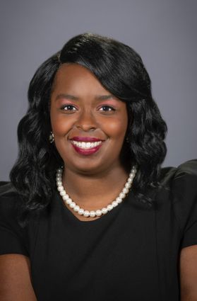 headshot of smiling Black woman in pearls and black dress