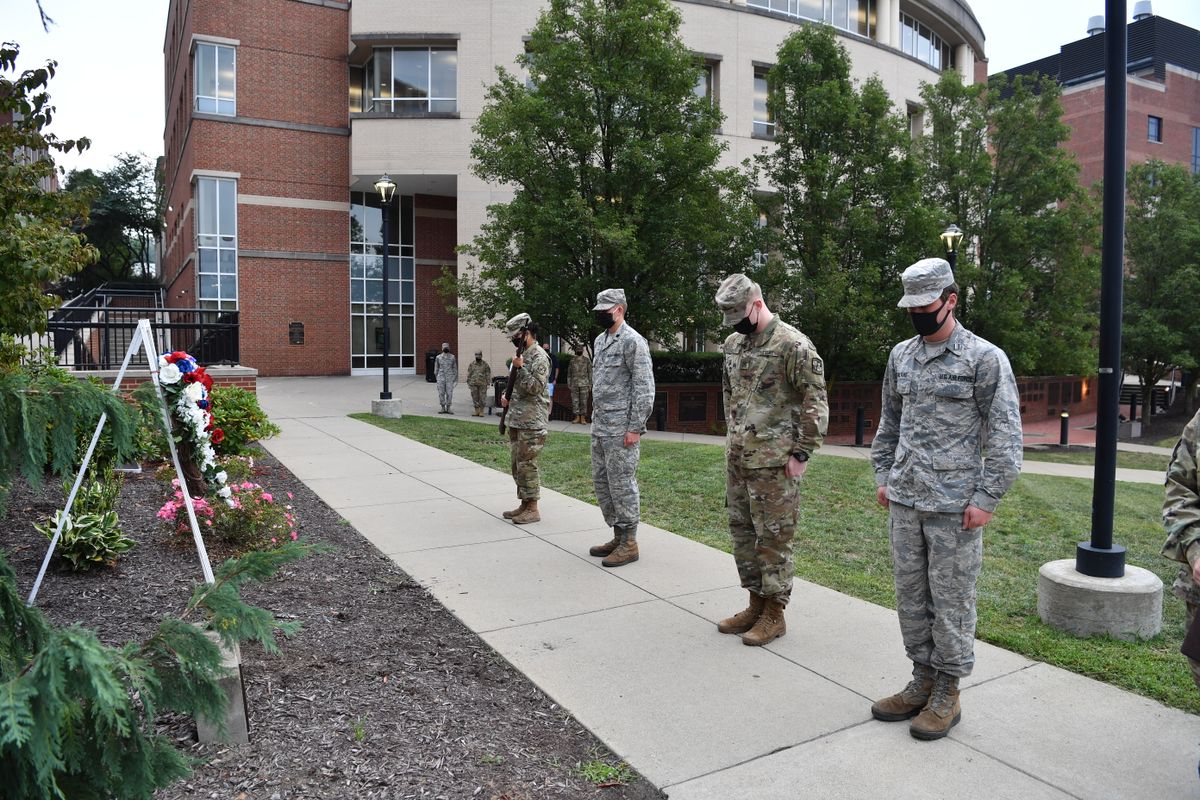ROTC Cadets stand in uniform, in front of a wreath
