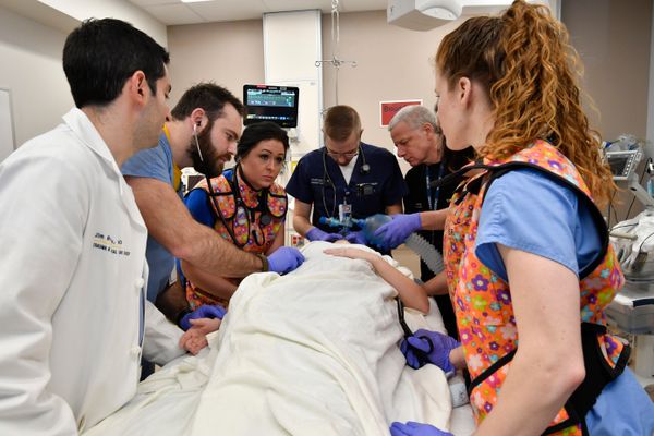 a group of medical professional gather around a patient in a hospital