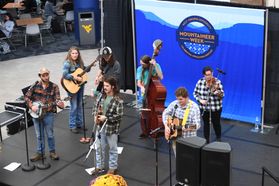 A 7-member bluegrass band performs on a black stage in the WVU Mountainlair during Mountaineer Week. 
