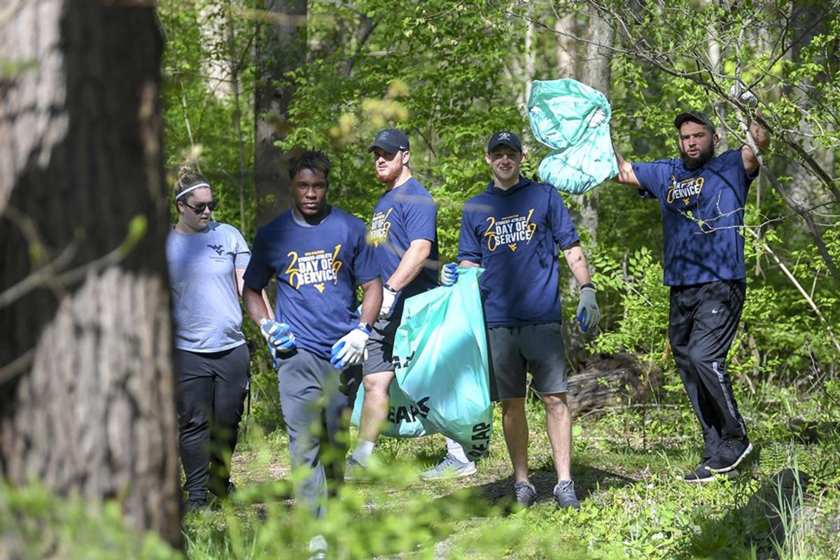 men and women pick up trash in a forest