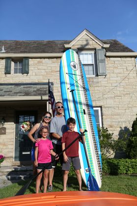 photo of a family standing with a paddleboard