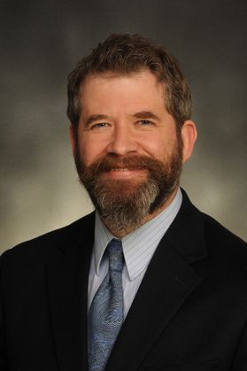 photo of smiling man with beard in suit and tie