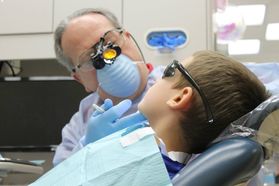 a dentist giving a boy wearing sunglasses an oral exam
