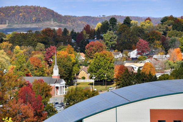 Picturesque image of a West Virginia countryside dotted with buildings, a church steeple and trees with autumn colors. 