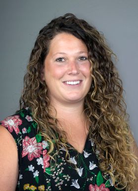 headshot of Luci Mosesso, WVU Extension 4-H agent for Pocahontas County. She is wearing a floral top and has long, curly, light brown hair. 