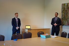 Two men in suits give a presentation in a meeting room