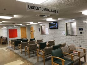 Waiting room full of chairs with an urgent care sign hanging from the ceiling. 