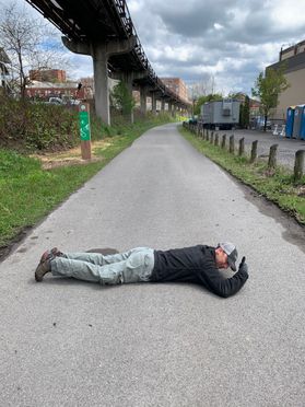 man lies down on paved trail