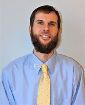 This is a portrait of Landon Southerly. Landon has short brown hair and brown beard and is wearing a blue button-up shirt and yellow tie.