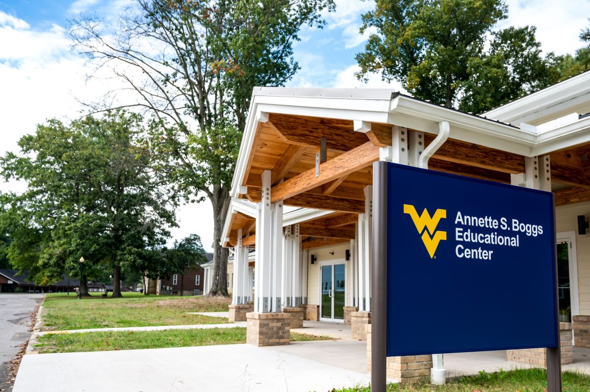 Photograph of new educational center at WVU Jackson's Mill. The building is featured in the right side of the photo as well as a blue sign that reads Annette S. Boggs Educational Center. There are trees and blue skies also in the photograph. 