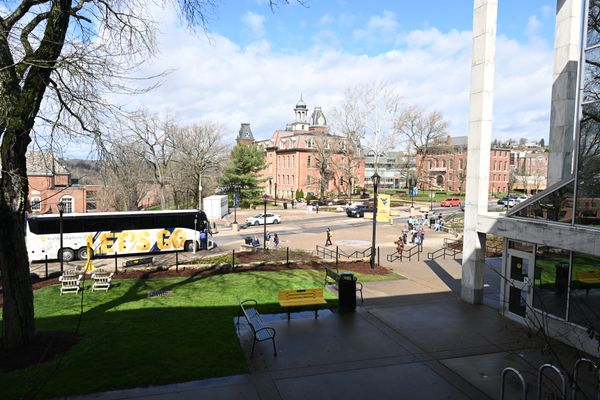 A wide shot of one of the main areas on the WVU campus. There is a white tour bus with the words 