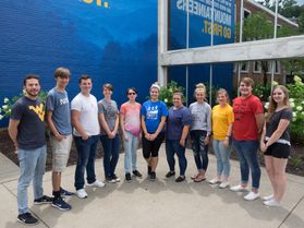 group of people stand in front of blue wall