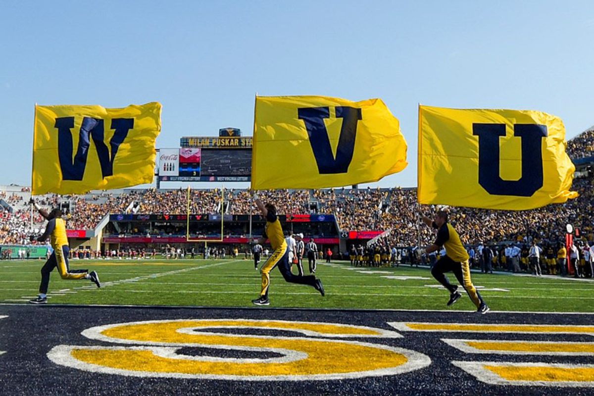 people carrying three flags WVU