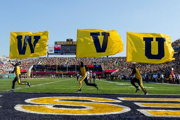 people carrying three flags WVU