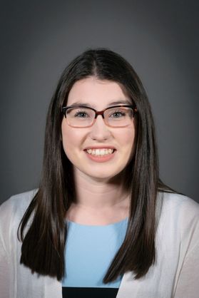 portrait of smiling young woman with long dark hair wearing glasses