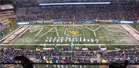 A football field is shown with band members in formation spelling out the word Macy's.