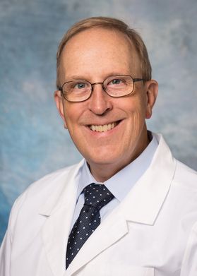 portrait of a smiling man in glasses wearing a white coat