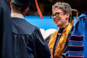 woman in glasses smiles at graduate