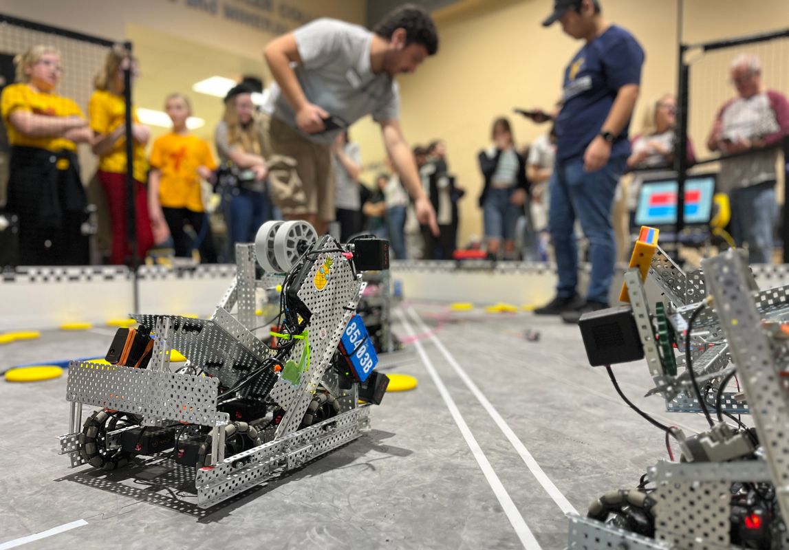 A crowd of students observe a robotics competition.