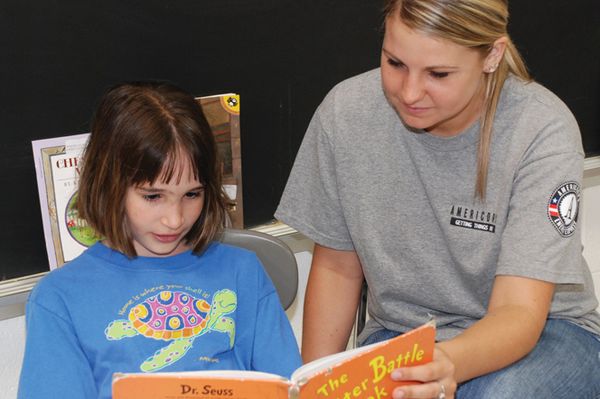 AmeriCorps volunteer reads with an Energy Express student