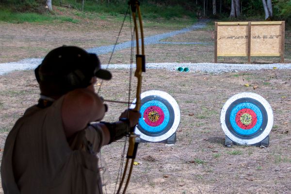 man with bow and arrow aims at target