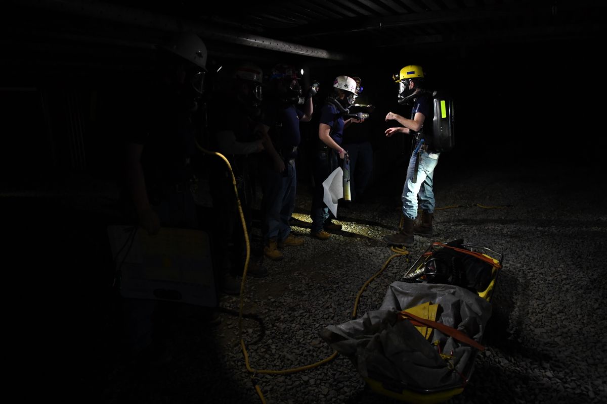 men wearing hard hats and head lamps work in a dark space