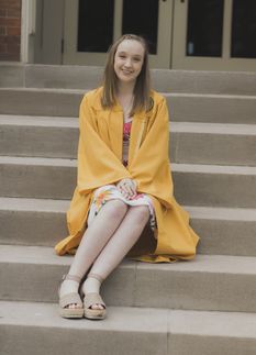 young woman, seated on steps, commencement gown