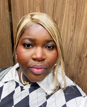 Portrait of Stephanie Sarfo, she has pulled back blonde hair and is wearing a collared shirt with a vest over. 