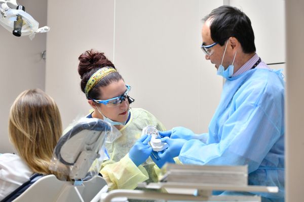 man and younger woman in scrubs look at model of teeth