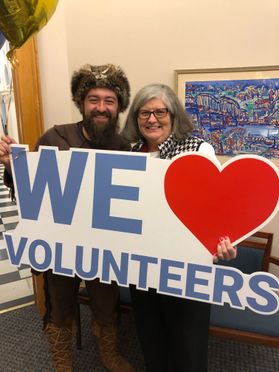 WVU Mountaineer with woman and sign that says WE love Volunteers