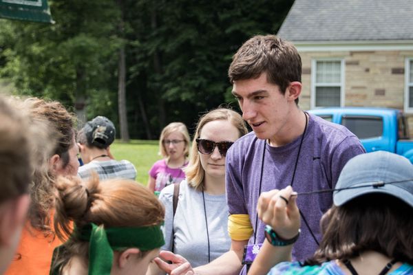 Young man in purple shirt talks to a group of people