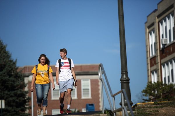 students walk across a college campus